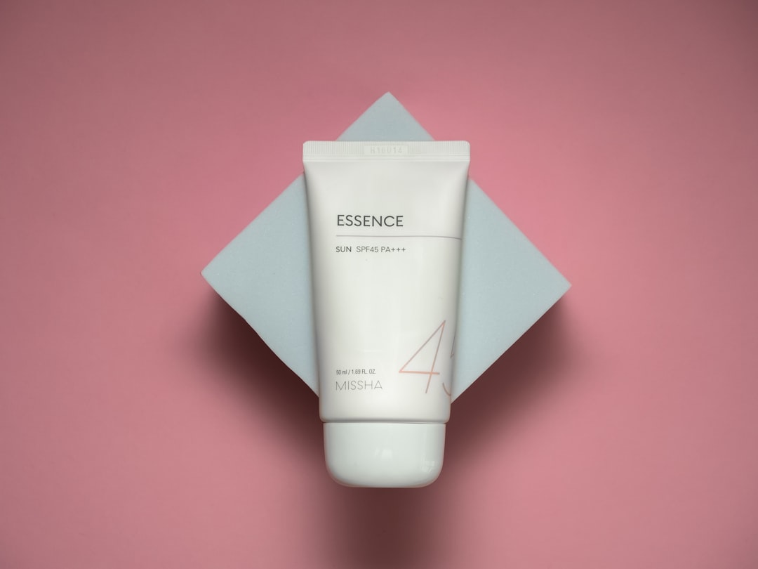 a tube of cream sitting on top of a pink surface