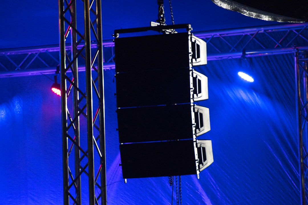Professional PA speakers hanging from a stage rigging truss at a live event