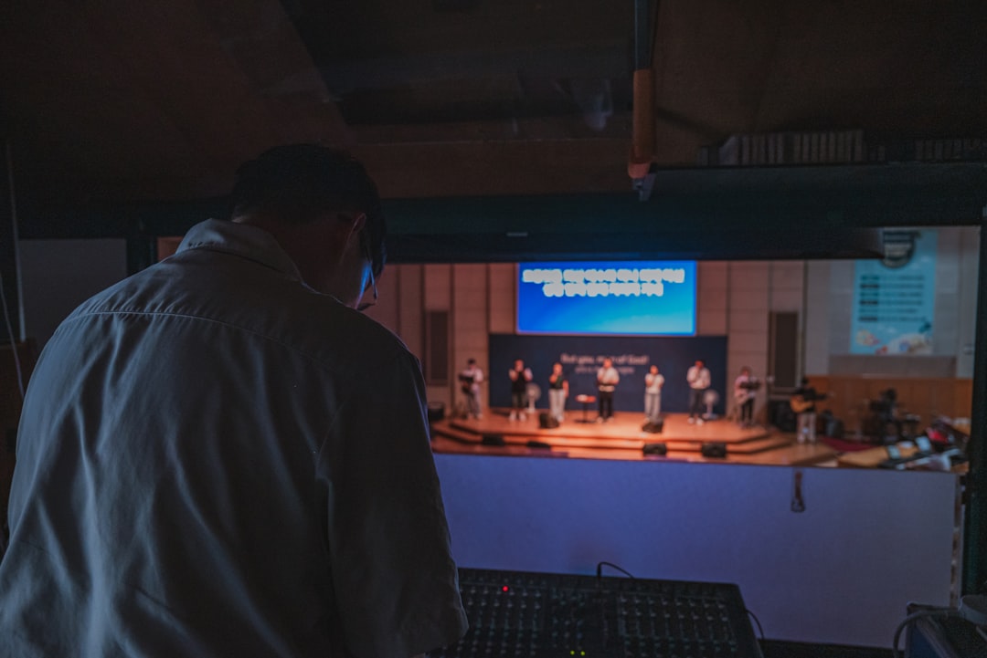 Sound technician at mixing board watching performance on stage