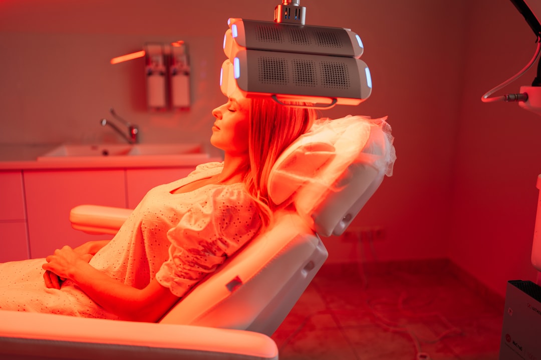 Woman receiving red light phototherapy facial treatment at spa