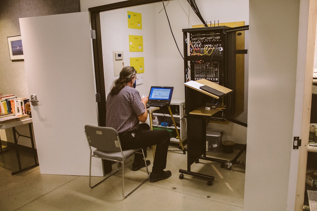 IT technician checking cable connections behind conference room AV equipment