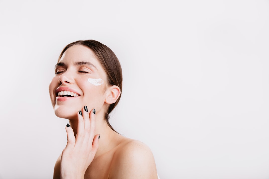 Woman with clear skin touching her jawline after clinical acne treatment